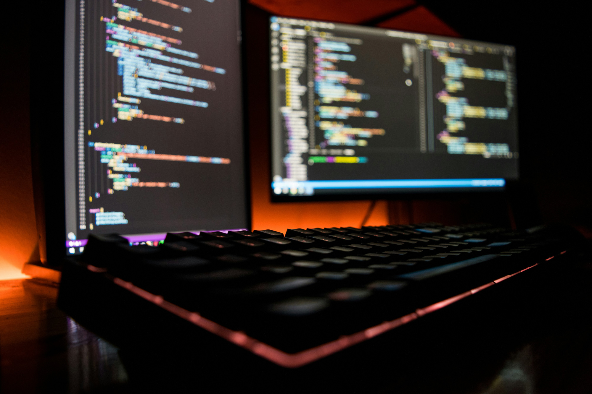 Arbeitsplatz mit Tastatur und zwei Bildschirmen, auf denen Programmcode für Webdesign und Webentwicklung angezeigt wird.